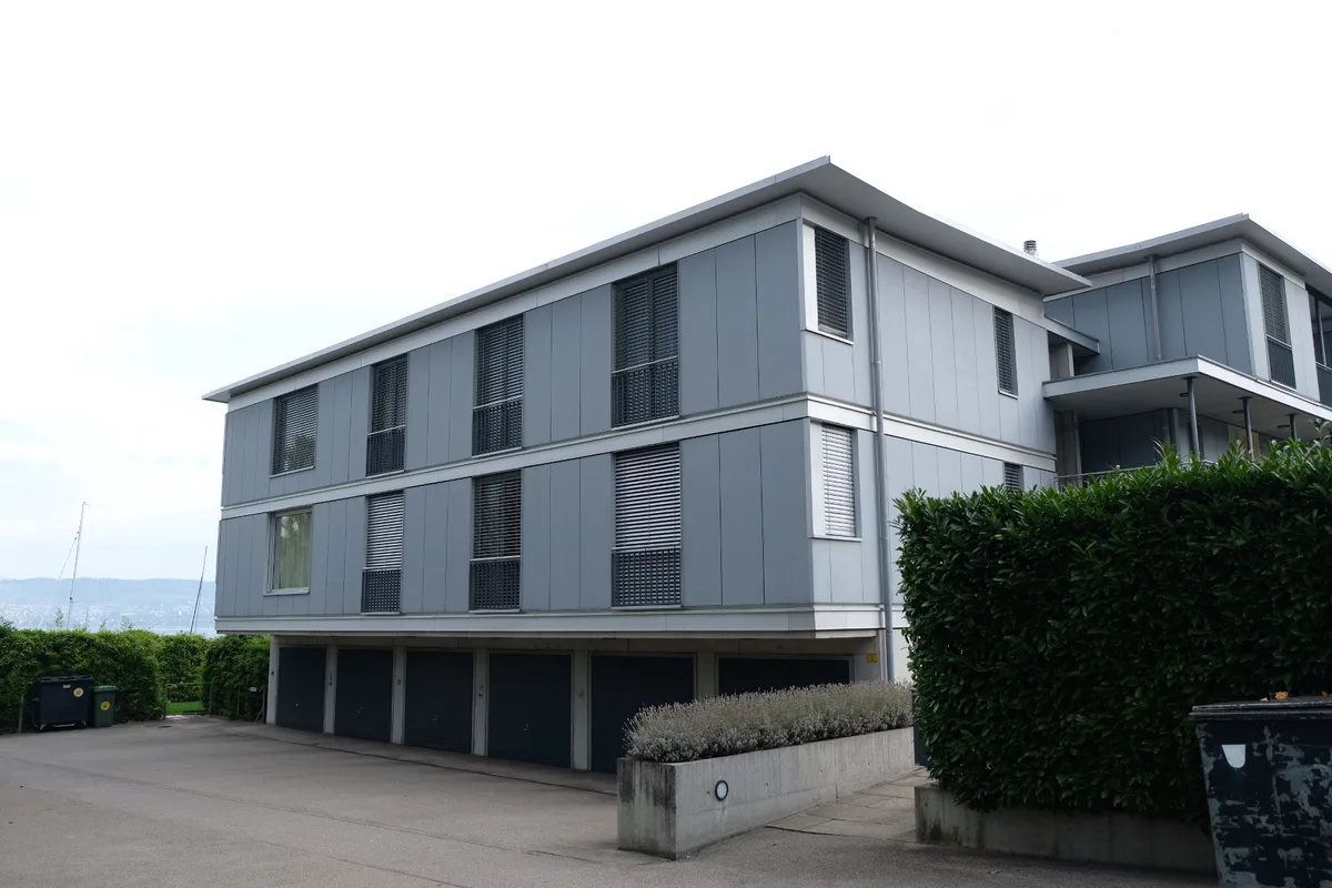 Dreigeschossiges Mehrfamilienhaus aus Glas und mit Flachdach.